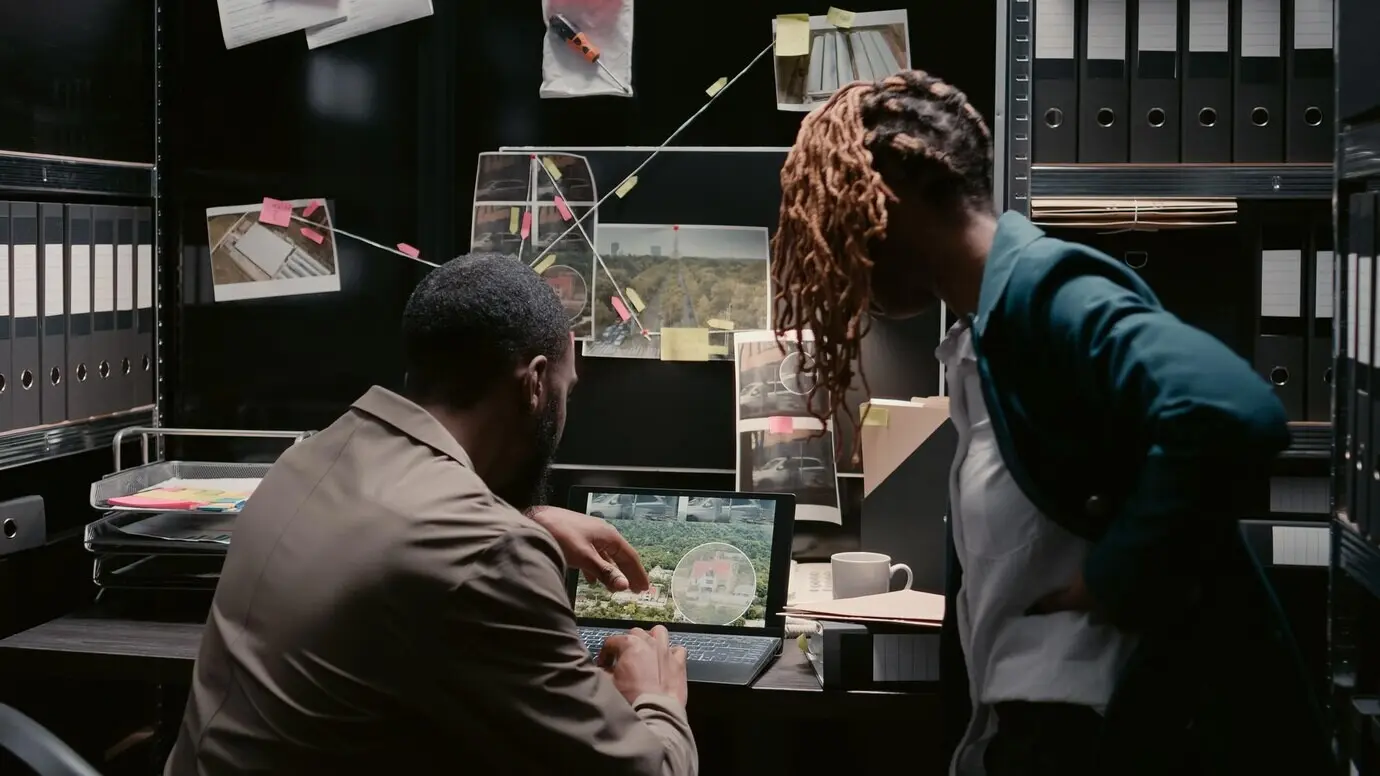 Afroamerikanische Polizeibeamte sichten Strafakten im Einsatzraum und planen im Polizeiarchiv eine private Ermittlung. Ein Mann und eine Frau, beide Investoren, analysieren Fallakten und lesen Aussagen.